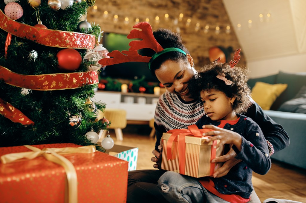 Happy African American mother and daughter opening Christmas presents