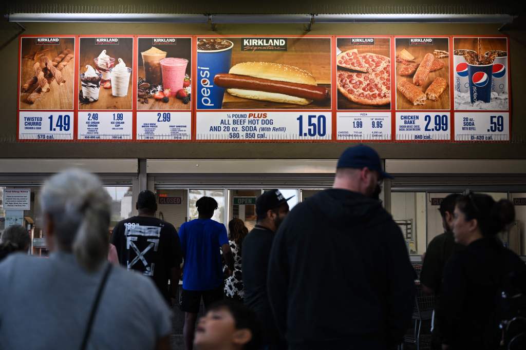 Customers waiting in line to order Hot Dog and Hot Soda Combos at a Costco Food Court under an alert