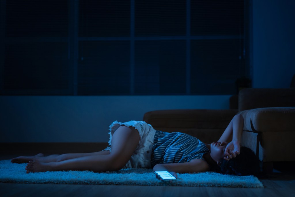 A stressed woman lying on the floor, overloaded by social media