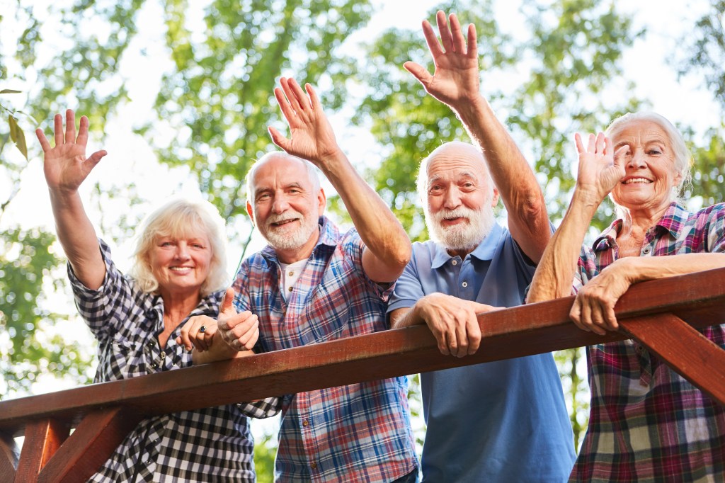 Happy elderly shaking from a bridge on a summer walk.