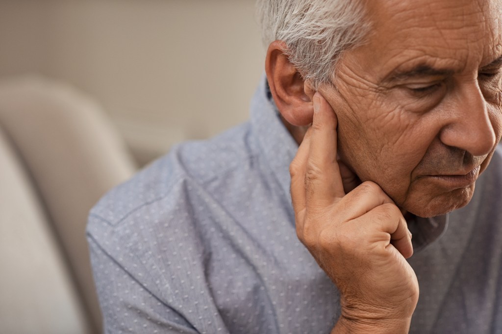 Side view of an elderly man who experiences an ear pain.