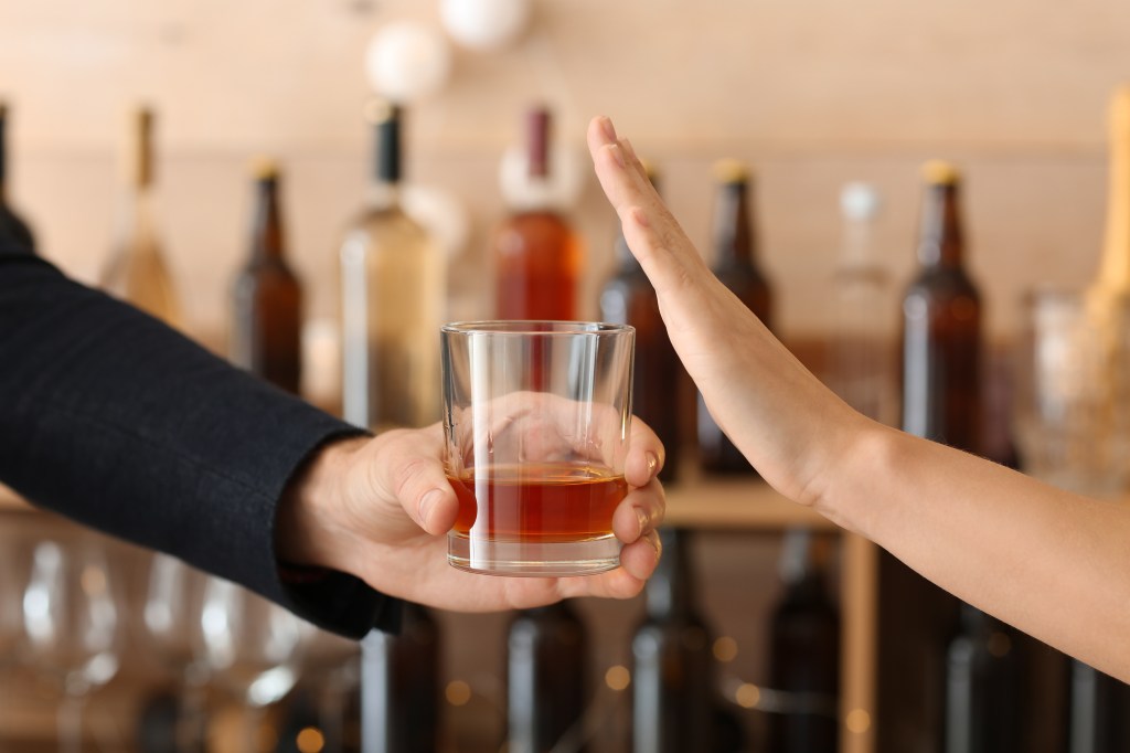 Hand by shaking a glass of alcoholic beverage