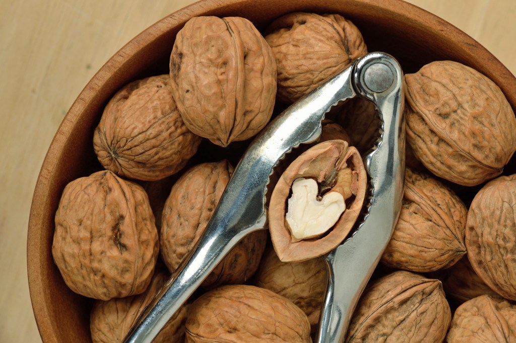 Nuts in wooden bowl with metallic nuts and heart -shaped walnuts.