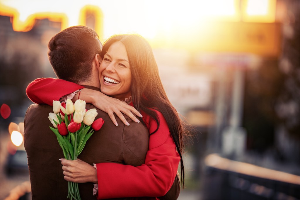 A young man surprising his girlfriend with a bouquet in a romantic gesture