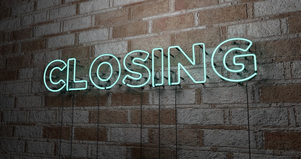 Neon -lit sign by reading 'closing' on a stone wall