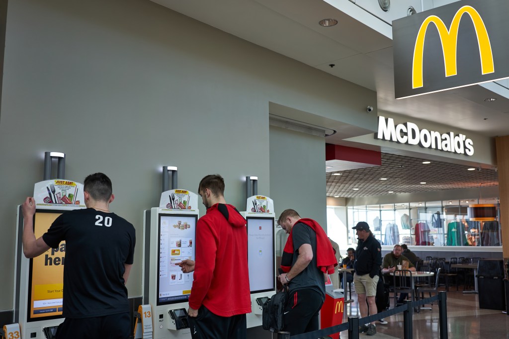 People who use self-service kiosks to place their orders at a McDonald's restaurant at Portland International Airport