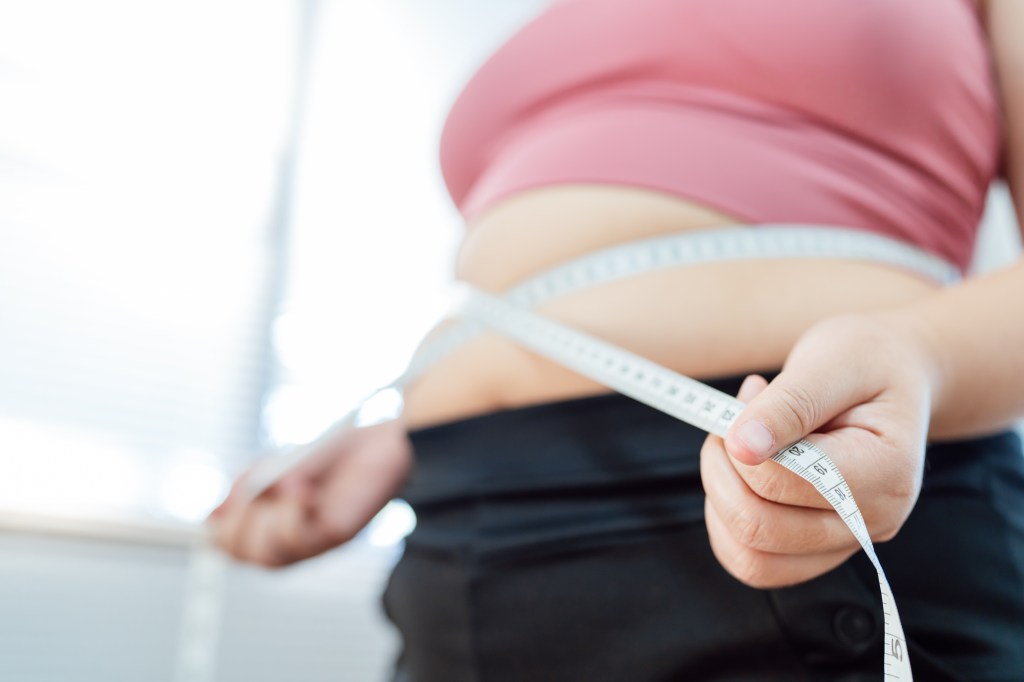 Overweight woman measuring waist, expressing the desire to lose weight for health