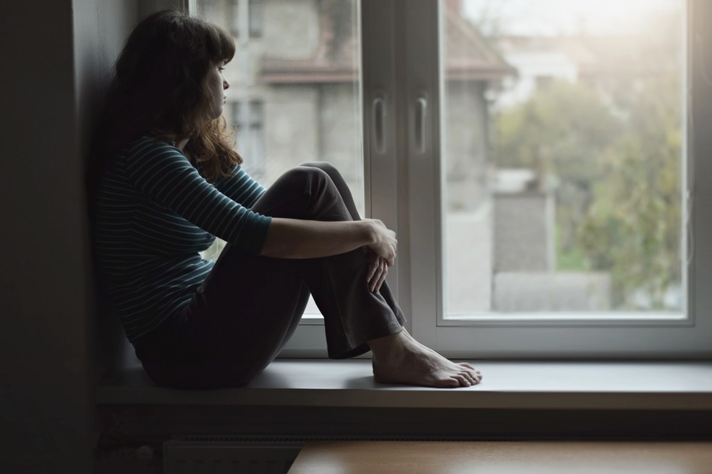 Depressed woman sitting in window of window