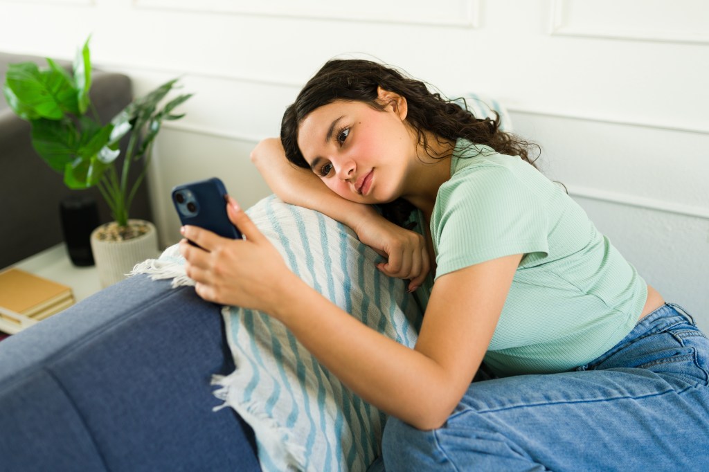 Teenage girl asking in anxiety as she waits for a text message on her phone
